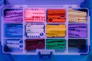 Clear aligner held next to traditional braces model