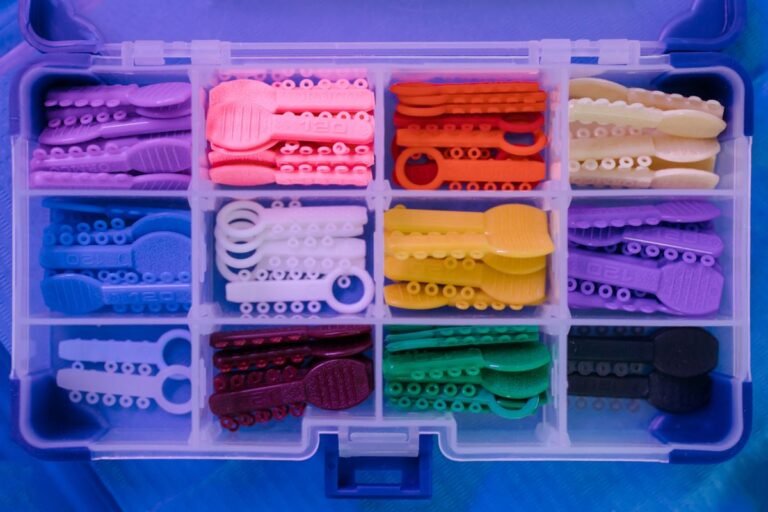 Clear aligner held next to traditional braces model